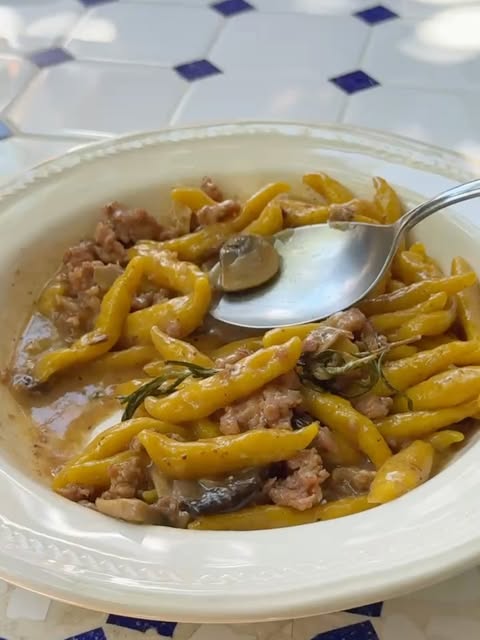 Capunti con hongos, salsiccia y pecorino en plato hondo blanco